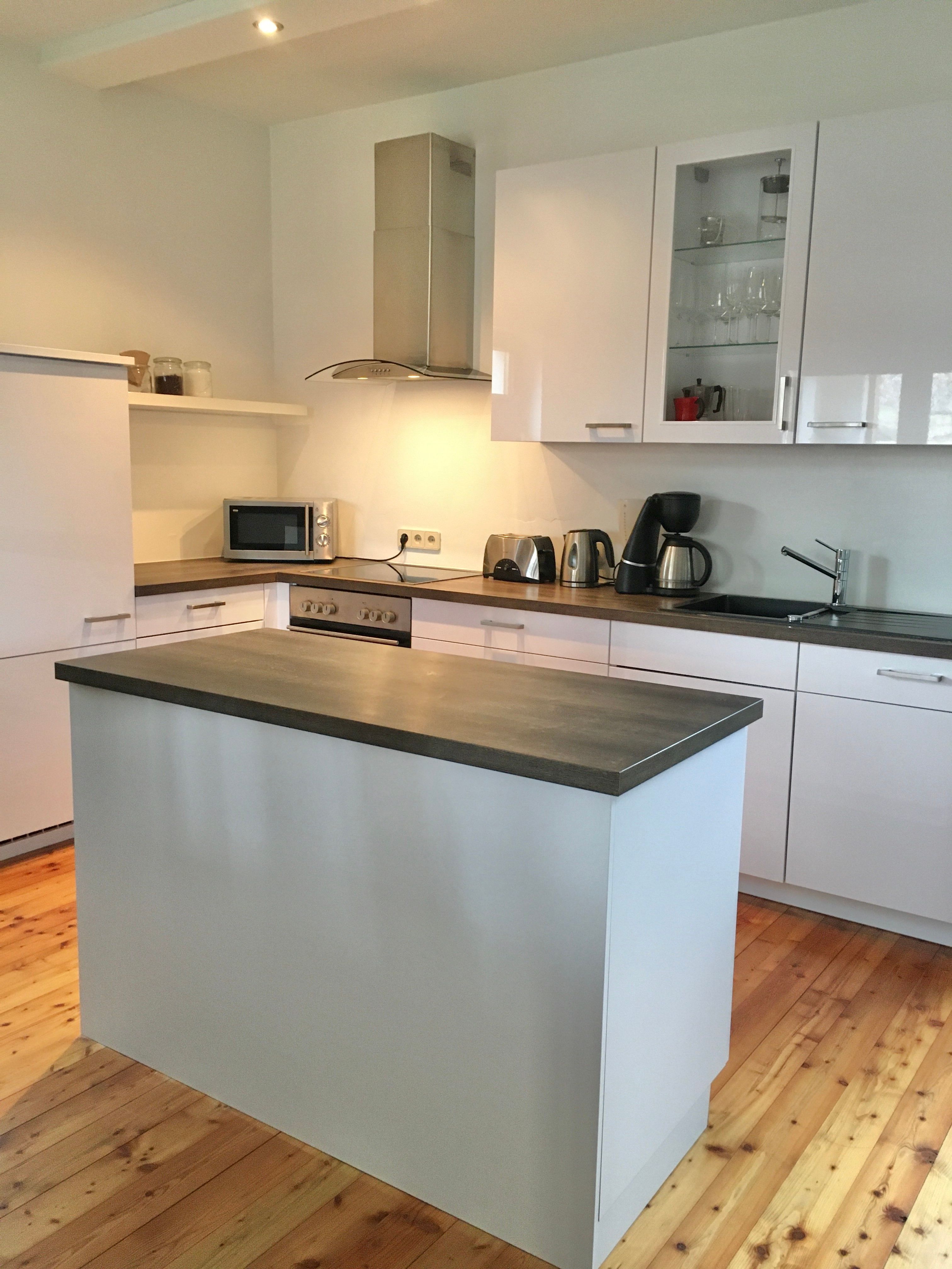 Modern kitchen with island, white cupboards and appliances.