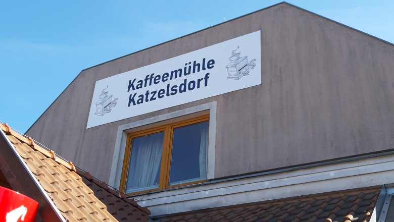 Building with sign 'Kaffeem&uuml;hle Katzelsdorf' and drawing of a coffee mill.