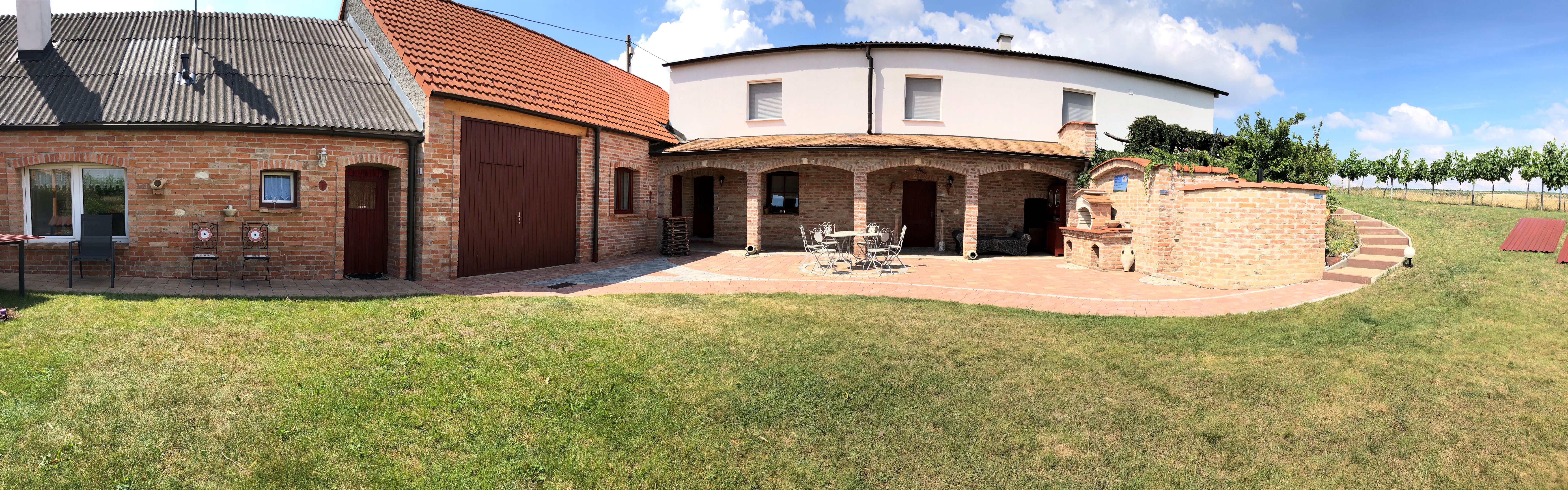 Brick building with garden and terrace in sunny weather.