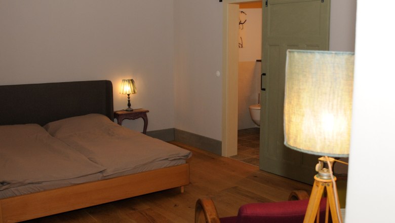 A cozy bedroom with double bed, bedside lamp and sliding door to the bathroom.