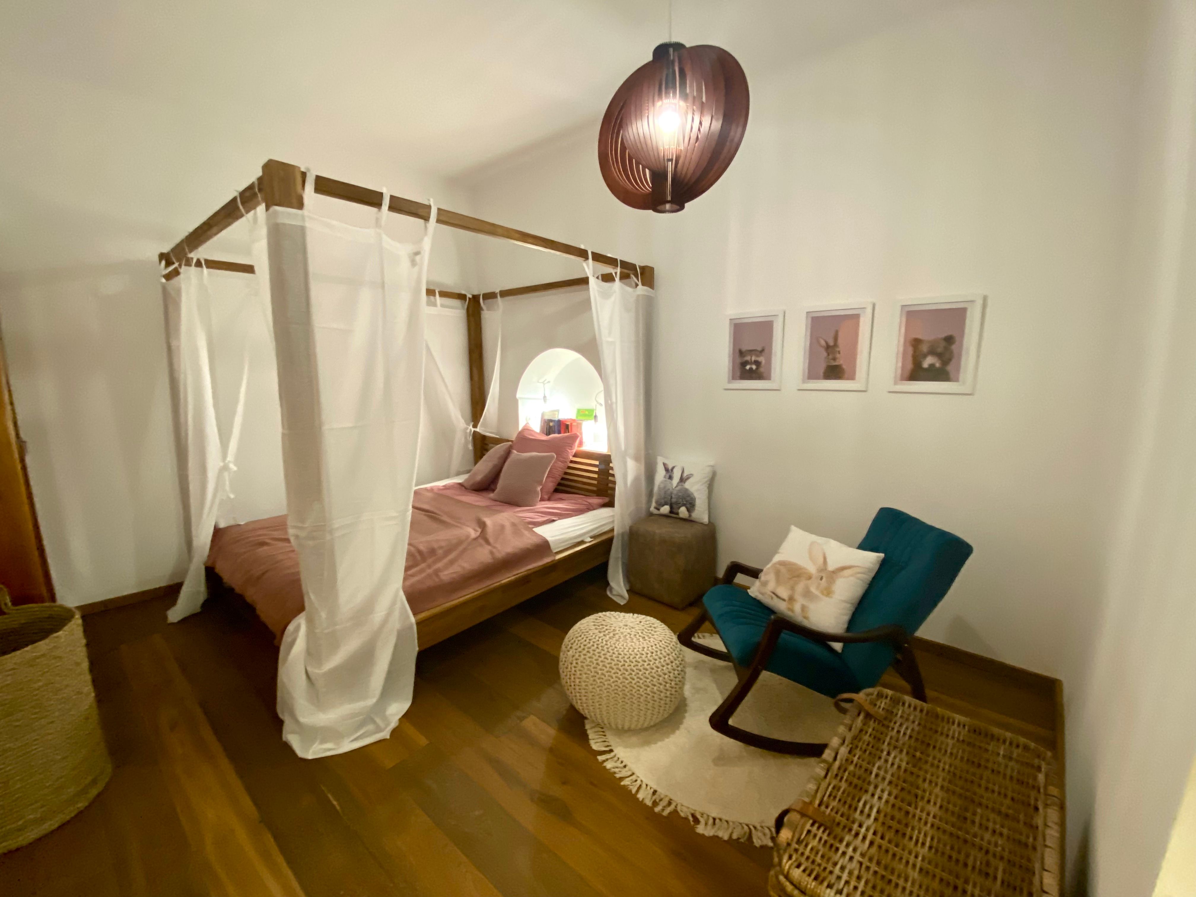 Cozy bedroom with four-poster bed, rocking chair and animal pictures on the wall.