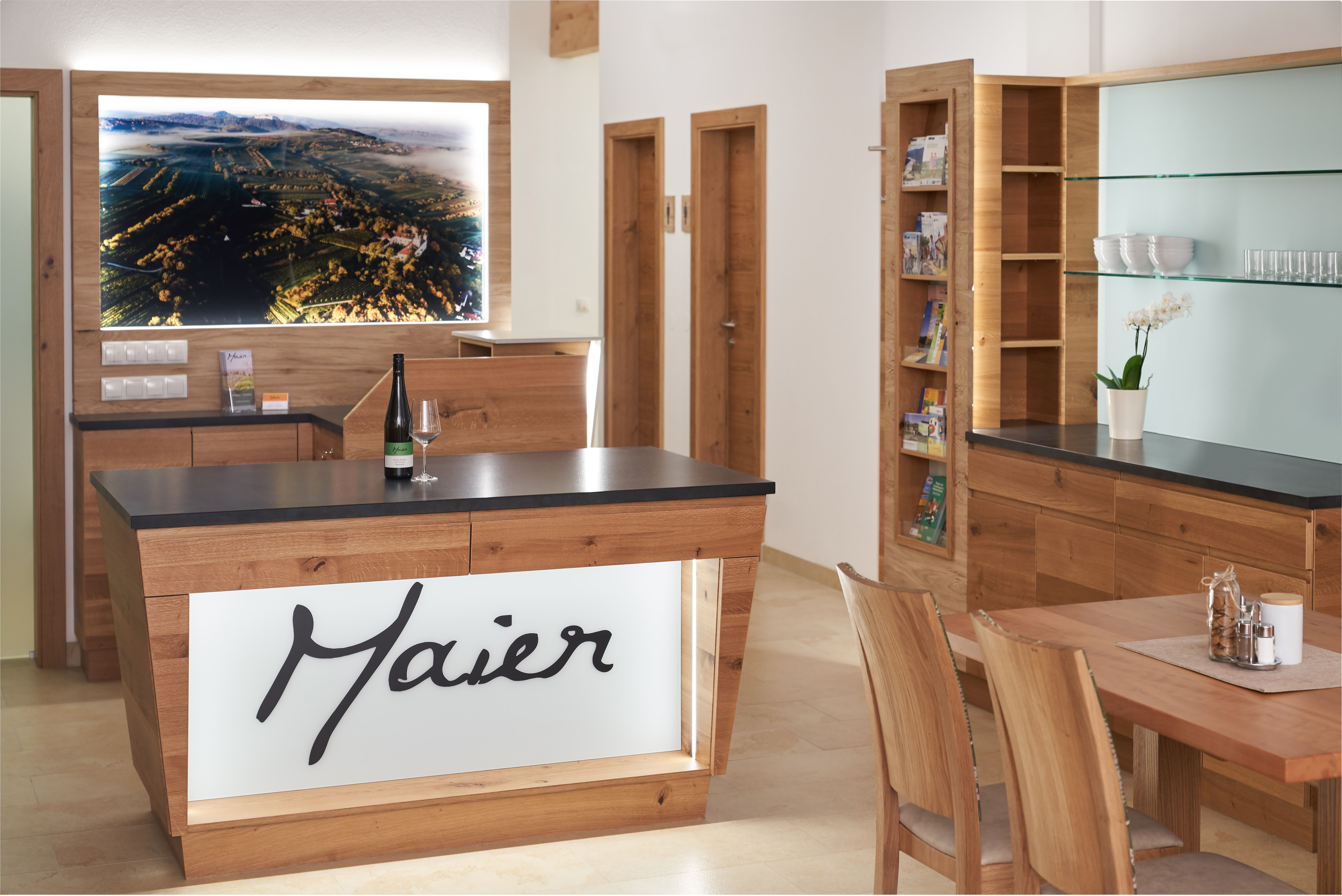 Interior view of a modern reception area with wooden furniture and a large landscape painting on the wall.