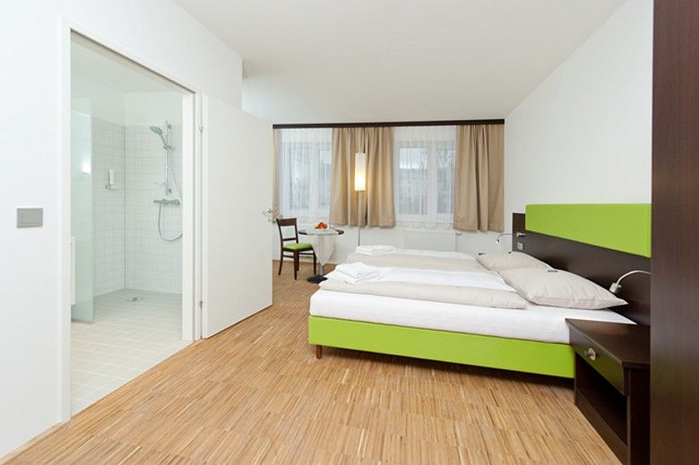 Modern hotel room with double bed, wooden floor and adjoining bathroom.
