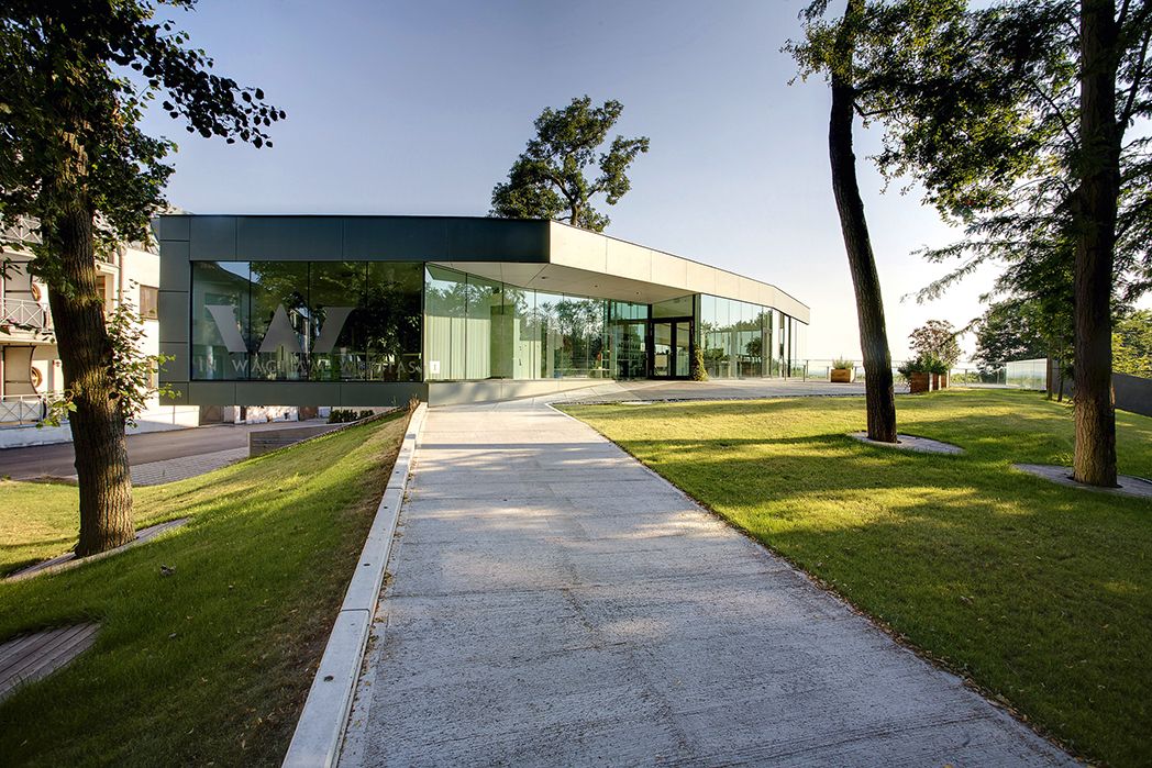 Modern glass façade of the Gebietsvinothek Weritas in Kirchberg am Wagram, surrounded by trees and manicured lawns.