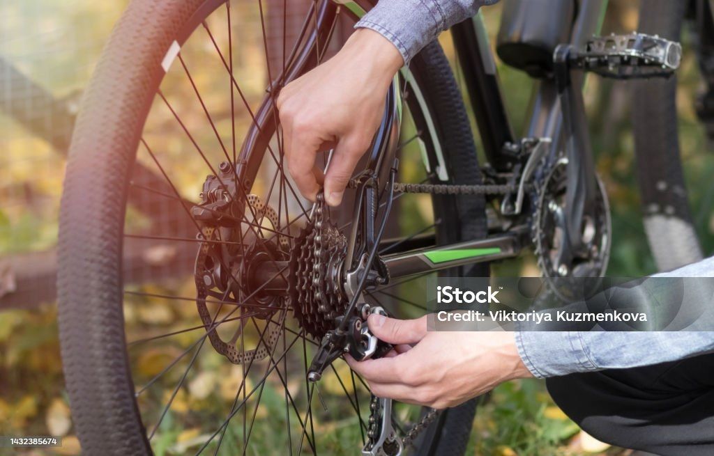 Person repairs bicycle chain outdoors.