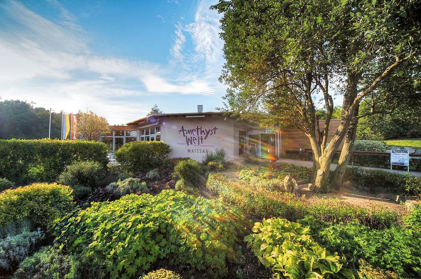 Entrance to Amethyst Welt Maissau with garden and trees in the foreground.
