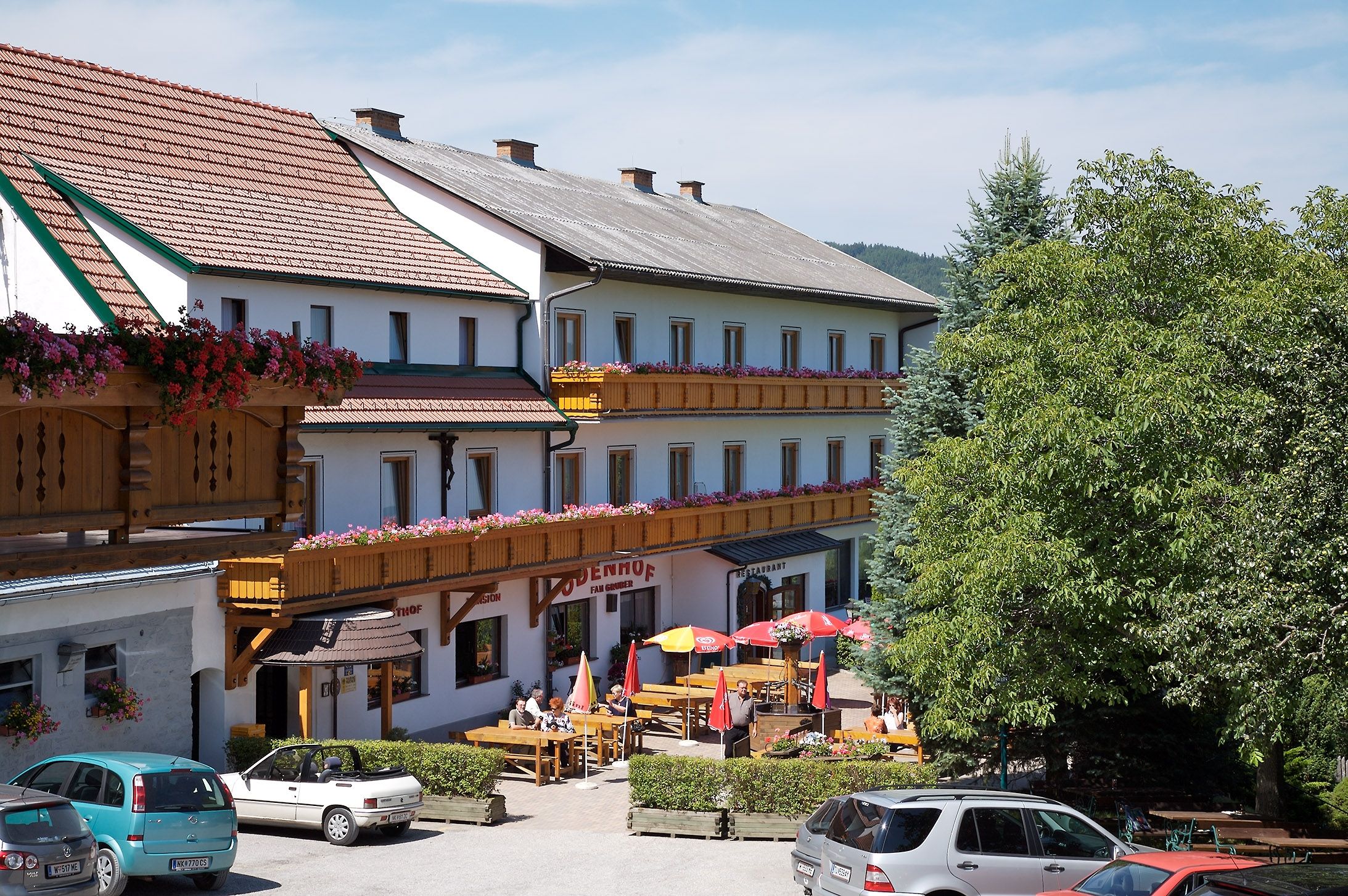 Gasthof-Pension Ödenhof with terrace and parked cars.