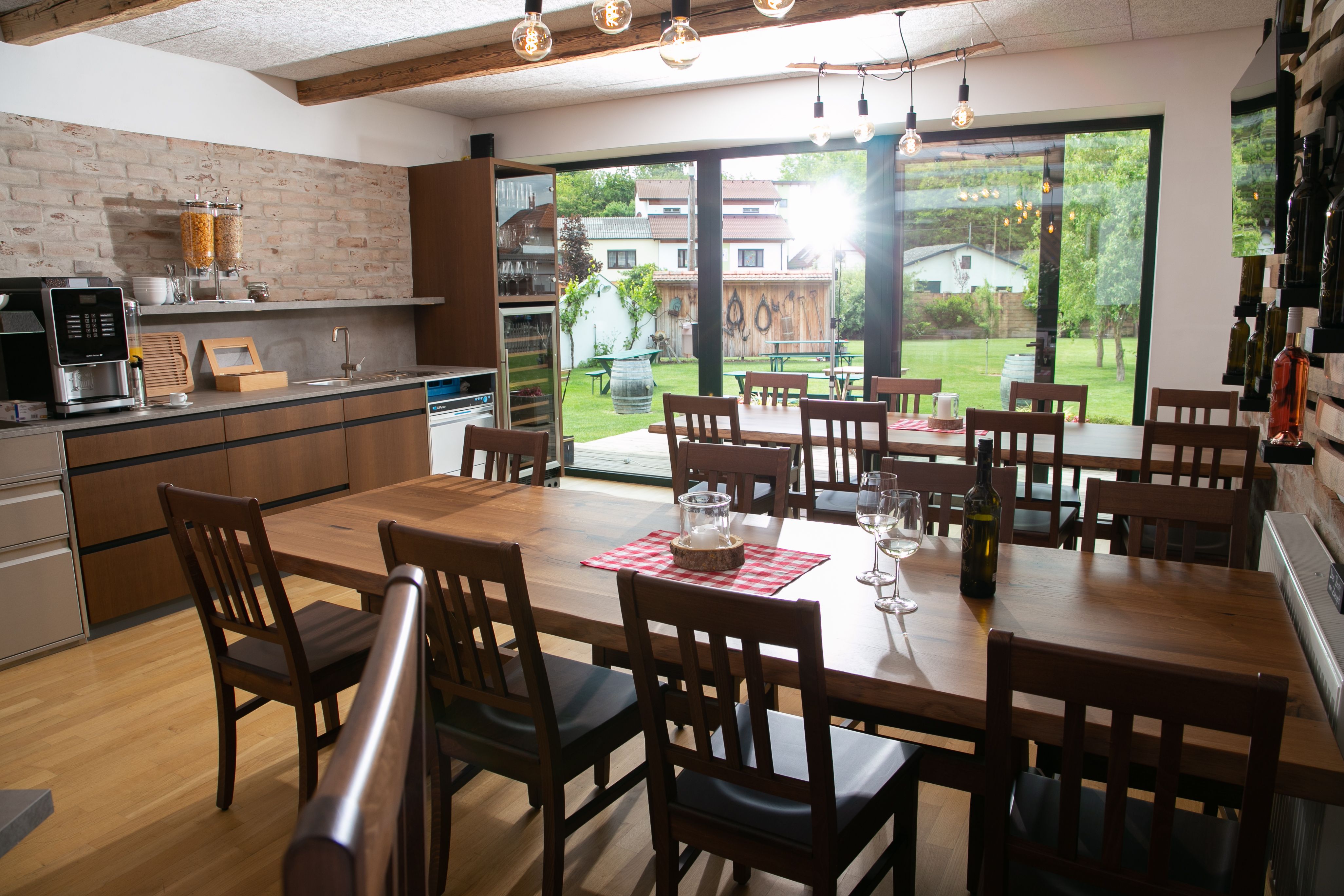 Interior view of a modern dining room with wooden tables and chairs, large windows and a view of a garden.