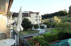 A hotel in the middle of a green landscape with a pond and sun loungers.