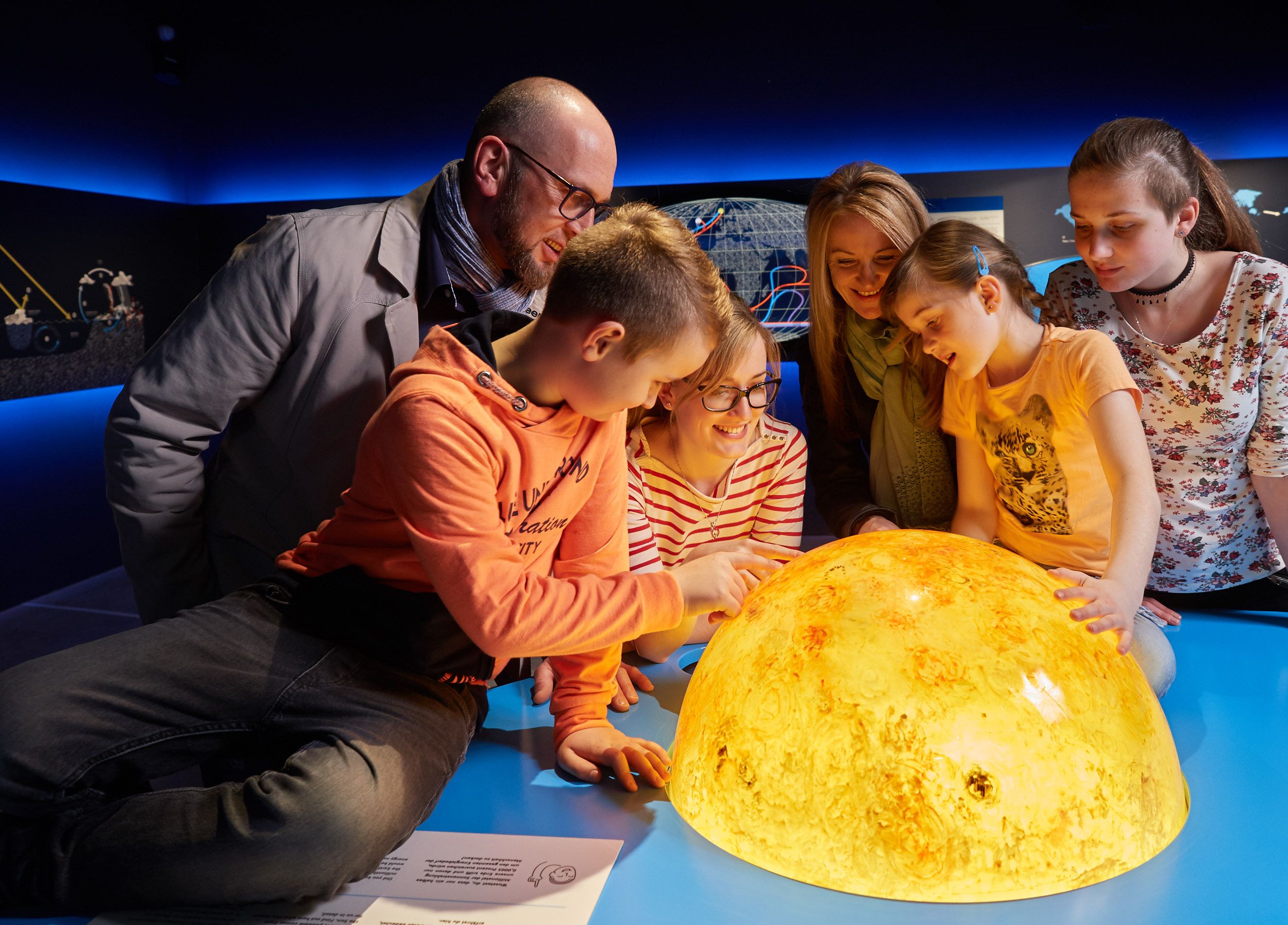Group of people looking at a luminous model of the sun.