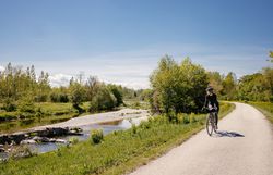 A picturesque cycle path meanders along a gently babbling brook, surrounded by lush greenery and flowering meadows. The clear air and bright sunshine invite you to enjoy the beauty of nature and unwind.
