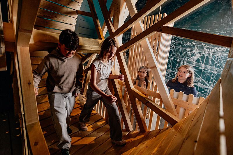 Children explore a wooden structure in a museum.