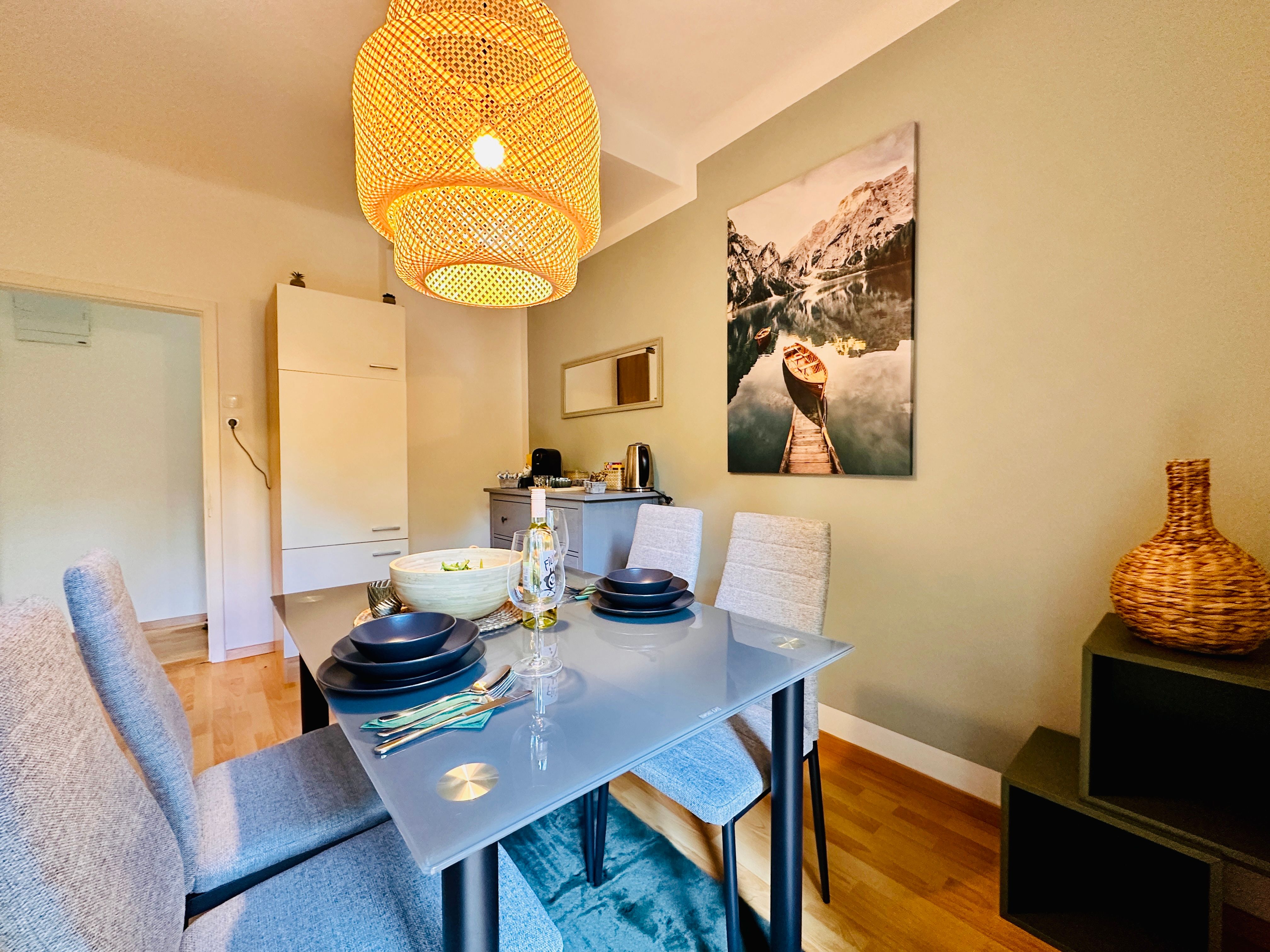 Dining room with glass table, gray chairs and large lampshade.