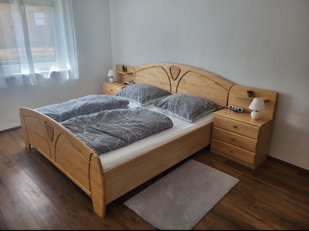 Bedroom with double bed, wooden furniture and gray bed linen.