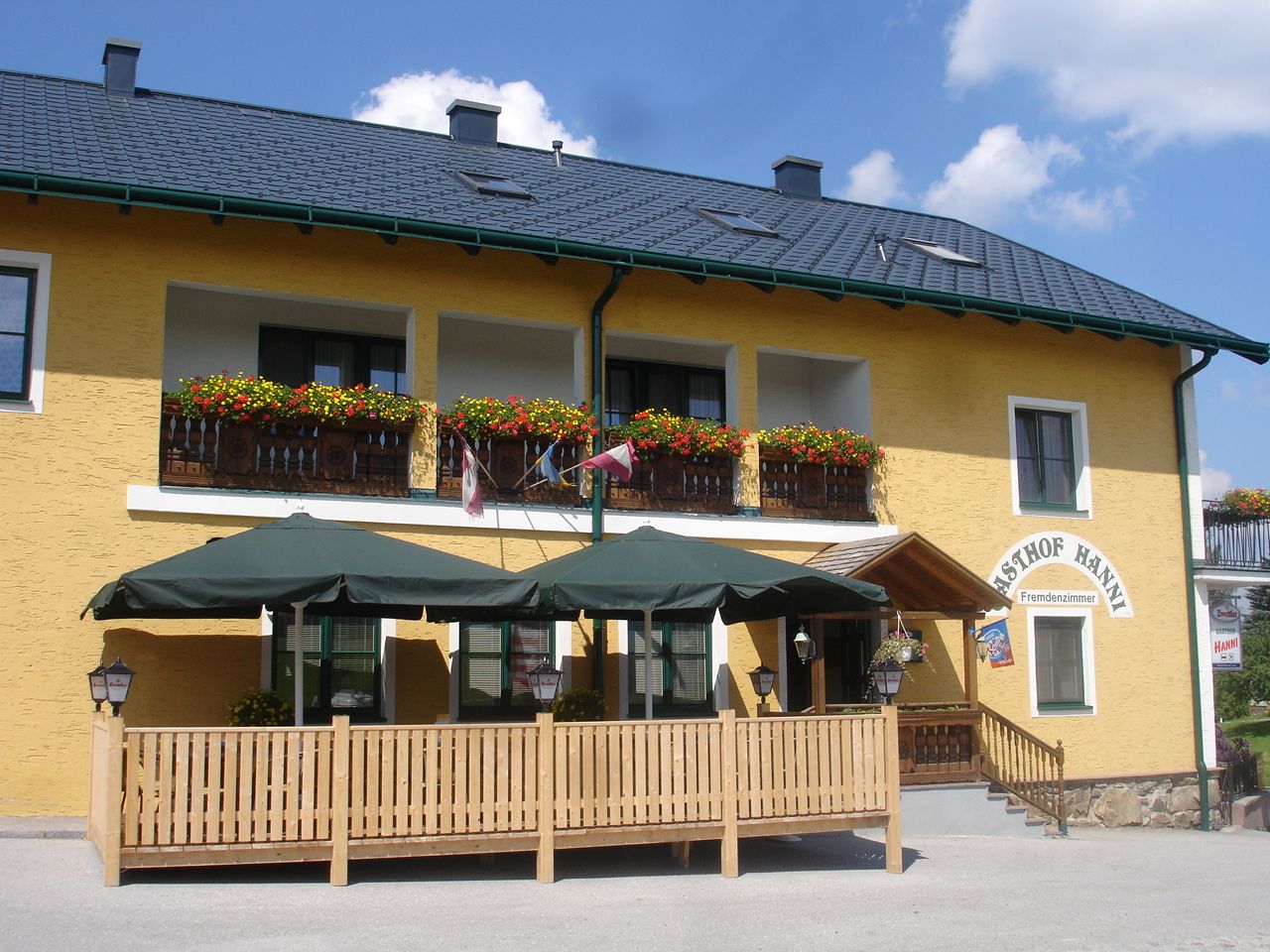 Yellow building with balcony, flowers and terrace with parasols.