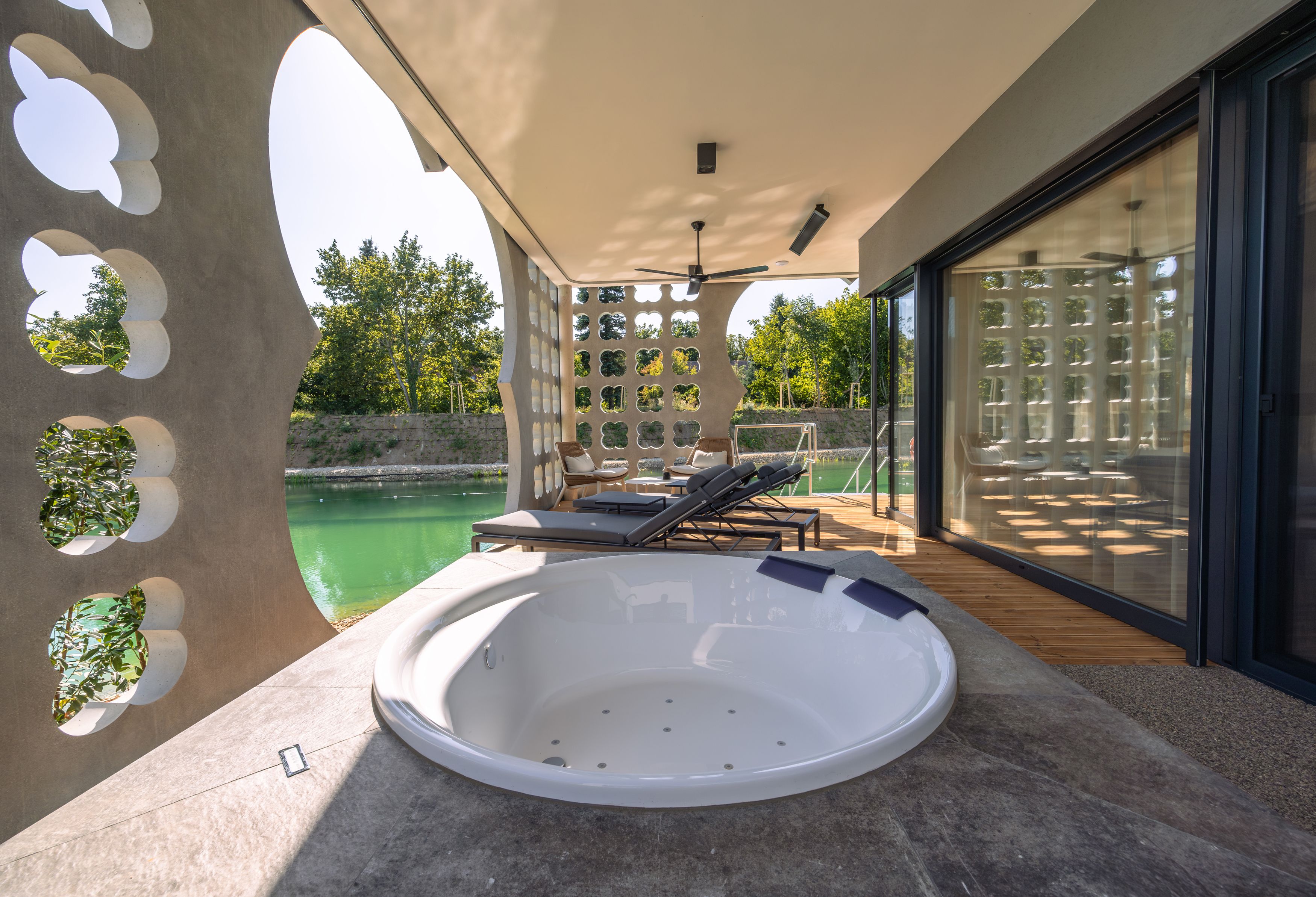 Terrace with whirlpool and sun loungers, view of a pond.