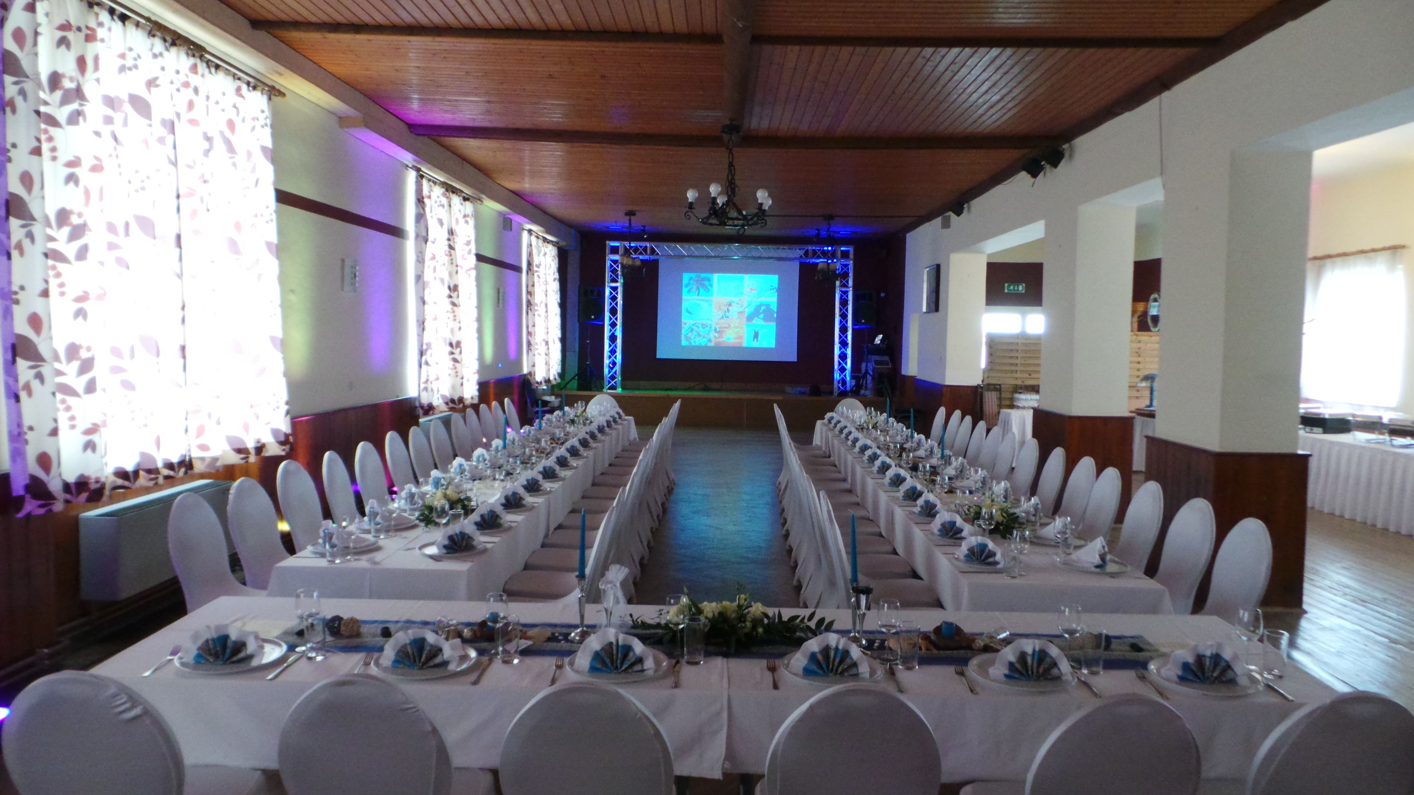 Festively decorated hall with long tables and projection screen.