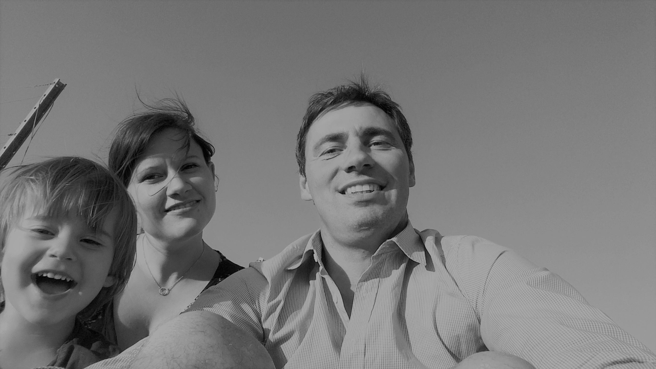 Black and white photo of a smiling family consisting of a man, a woman and a child looking into the camera.