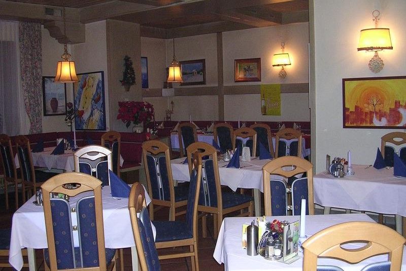 A cozy restaurant with wooden furniture, laid tables and wall decorations.