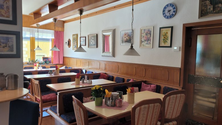 Cozy dining room with wooden furniture, decorative pictures on the wall and laid tables.