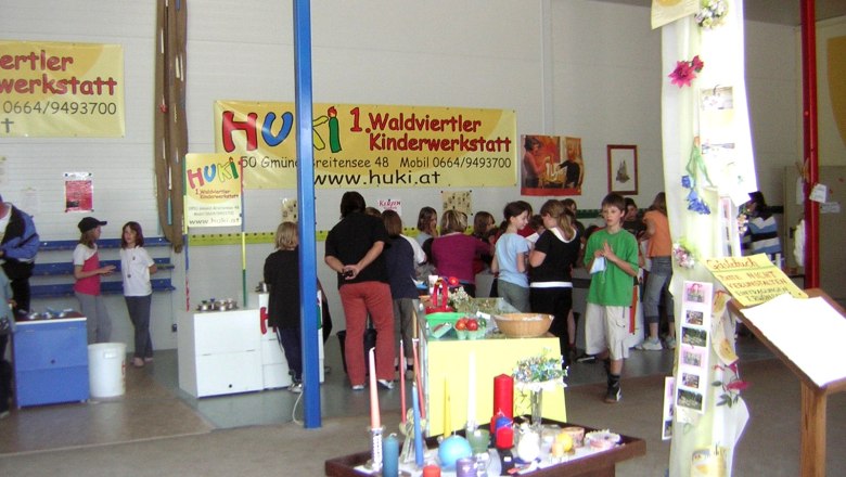 Interior view of a children's workshop with people and craft materials.