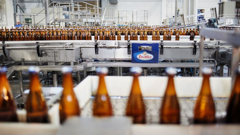 Bottles on a conveyor belt in a brewery with the Zwettler logo.