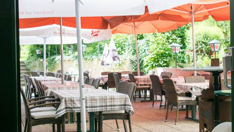 Outdoor area of a caf&eacute; with tables, chairs and parasols.