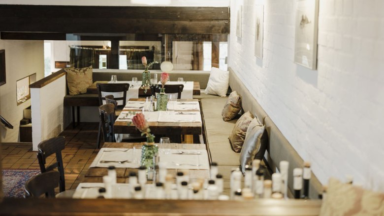 Cozy restaurant with wooden tables, cushions and subtle lighting.