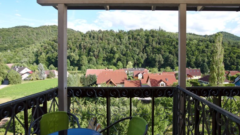 View from a balcony of a green landscape with hills and red roofs.
