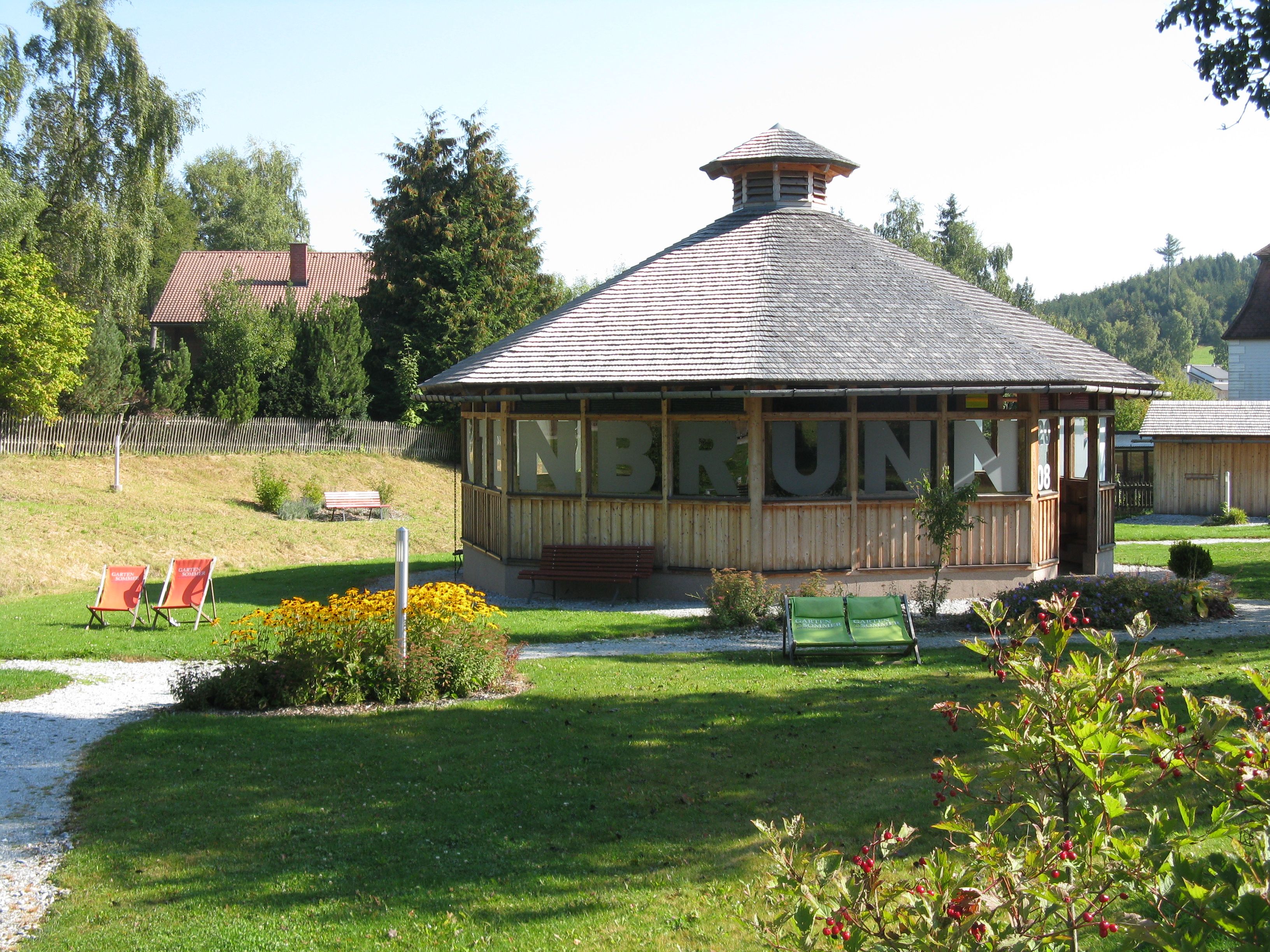 Pavilion in a green park with flowers and deckchairs.