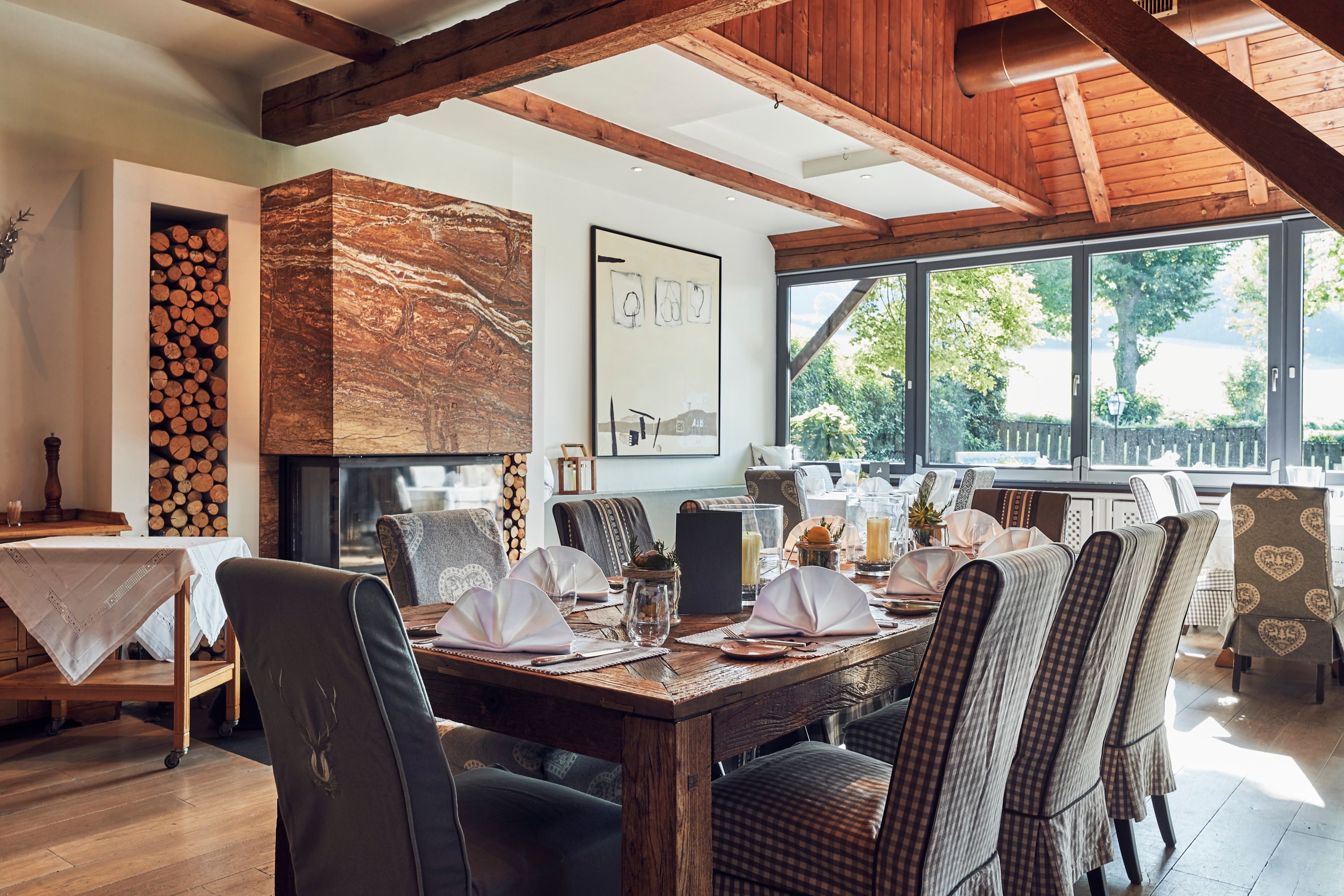 Elegant restaurant with wooden beams, fireplace and covered tables.