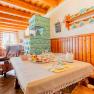 Cozy dining room with wooden furniture, set table and green tiled stove.