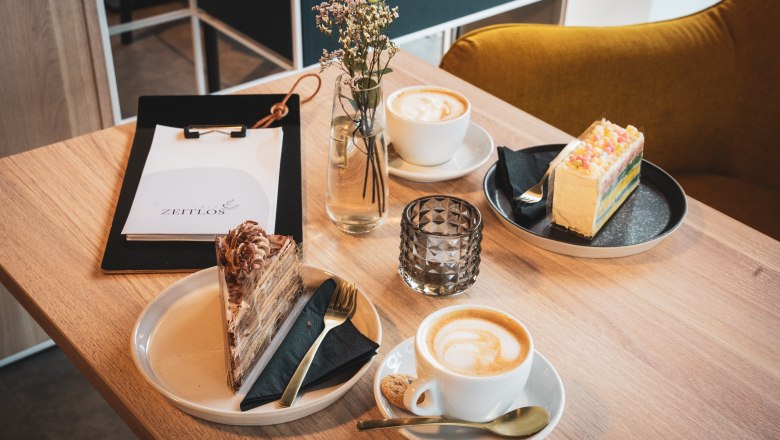 Caf&eacute; table with two cakes and caf&eacute;s with menu and flower.