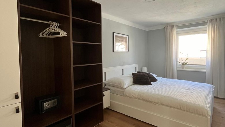 Modern bedroom with double bed, closet and window with curtains.