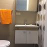 Small bathroom with washbasin, mirror, shower curtain and towels.