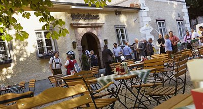 People in front of a traditional inn with a beer garden.