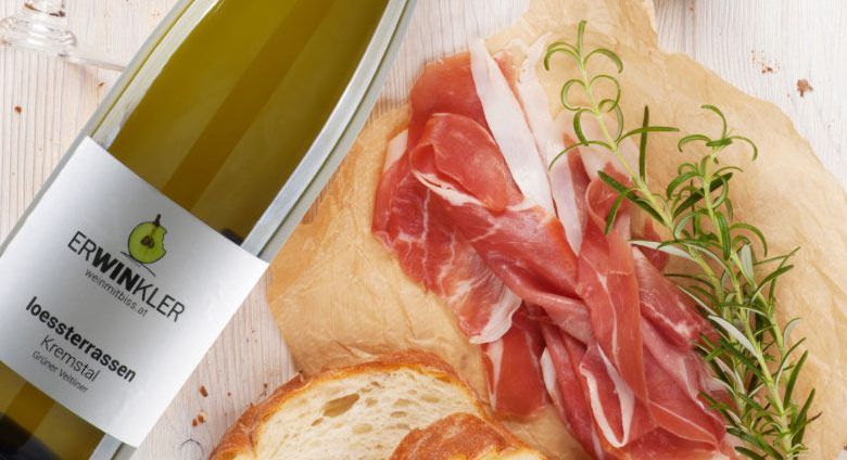 Wine bottle with ham and bread on a wooden background.