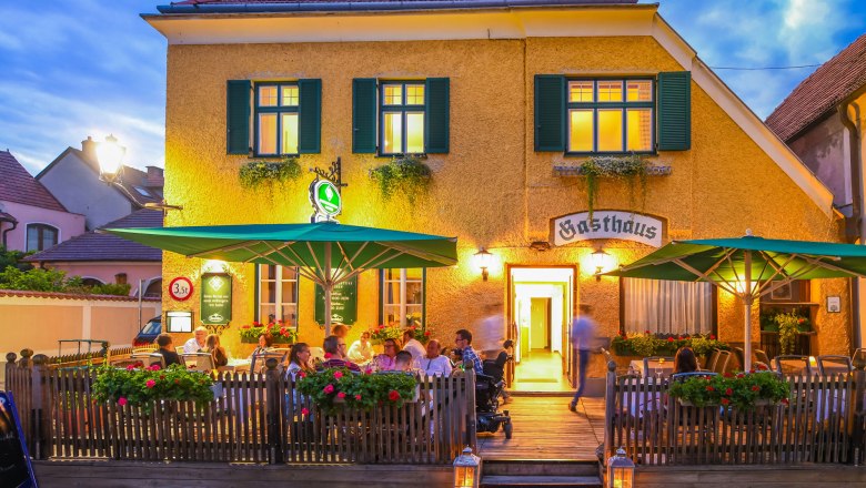 Exterior view of an inn with terrace and guests at dusk.