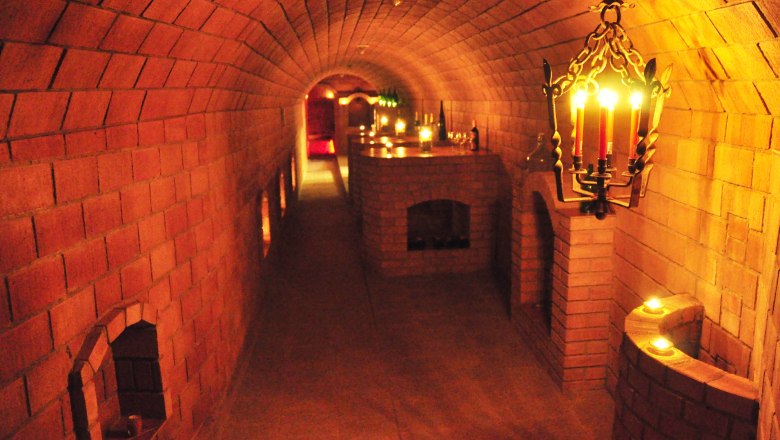 An illuminated wine cellar with brick walls and candlelight.