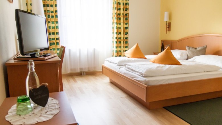 Comfortable hotel room with double bed, TV and curtains.