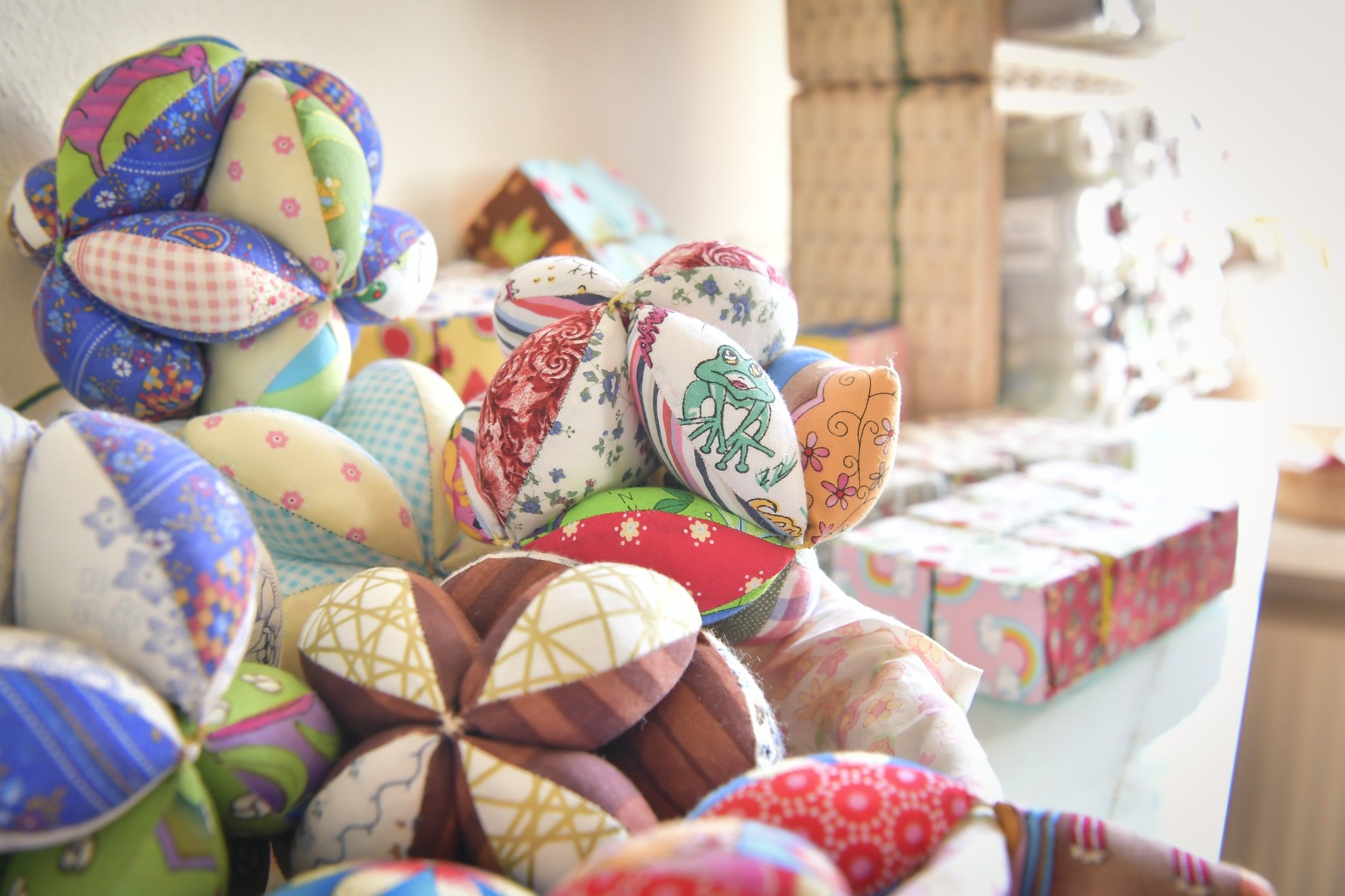Colorful, handmade fabric balls in different patterns and colors on a table.