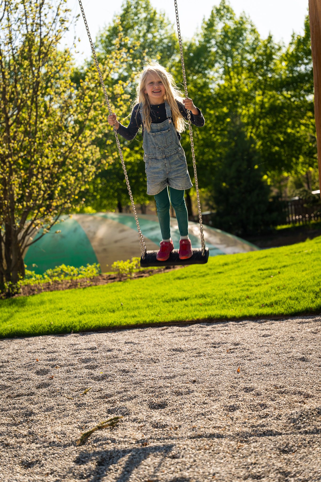 A child swings happily on a playground in the countryside.