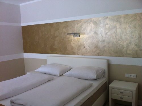 Modern bedroom with double bed and golden wall decoration.
