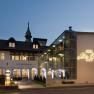 Exterior view of the Hotel Sacher Baden at dusk with illuminated lettering and historic building.