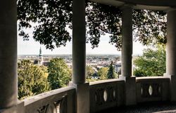 Von dieser malerischen Aussichtsplattform aus eröffnet sich ein atemberaubender Blick über die sanften Hügel und die charmante Stadt. Die üppigen Bäume spenden Schatten und laden dazu ein, die Ruhe der Natur zu genießen. Ein perfekter Ort, um die Seele baumeln zu lassen und die Schönheit der Umgebung zu erleben.