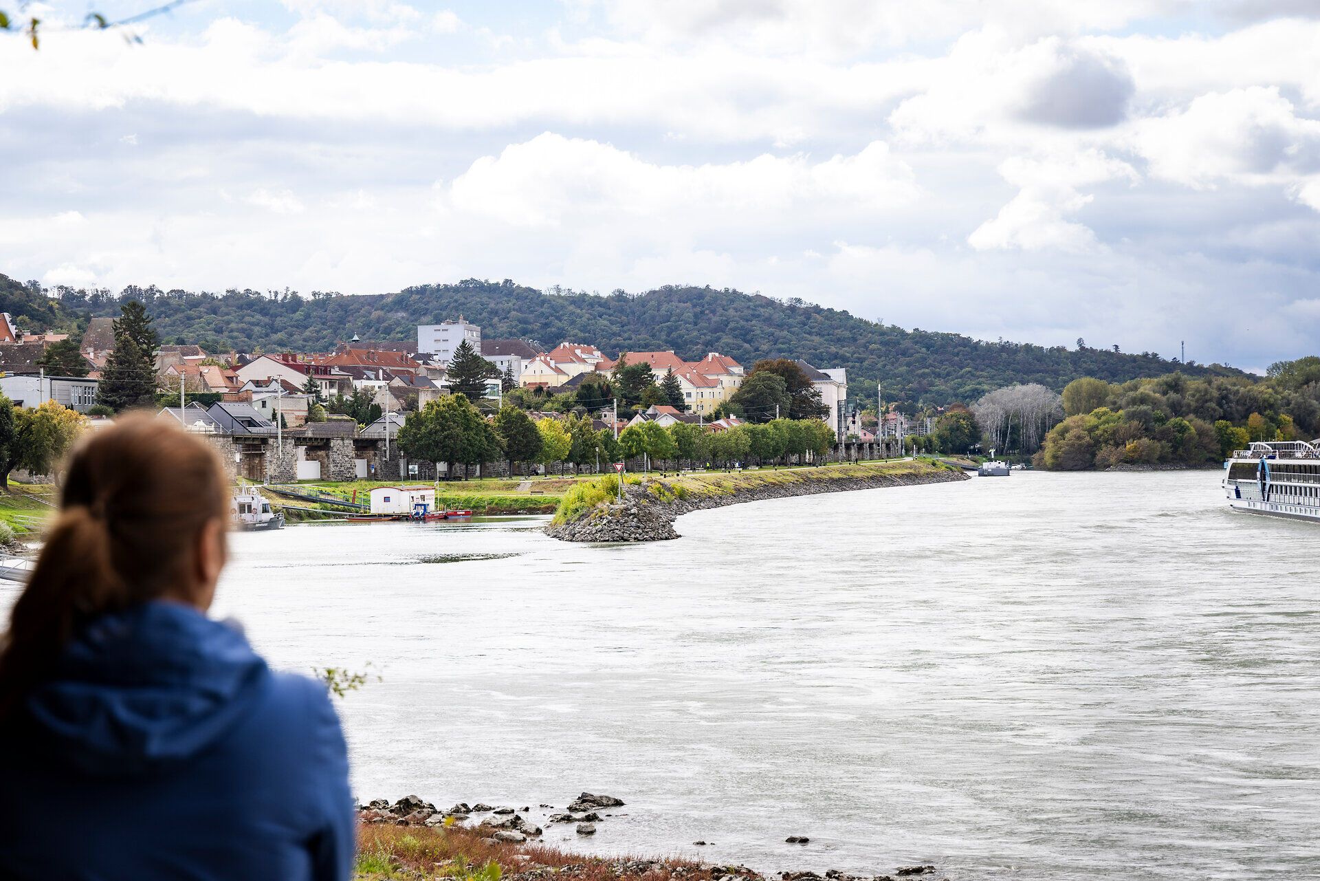 A woman looks out over the Danube and the houses of Hainburg on the banks of the Danube.