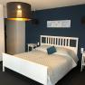A modern double room with a white bed, blue wall and stylish lamps.
