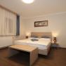 A simply furnished room with a double bed, wooden furniture and curtains.
