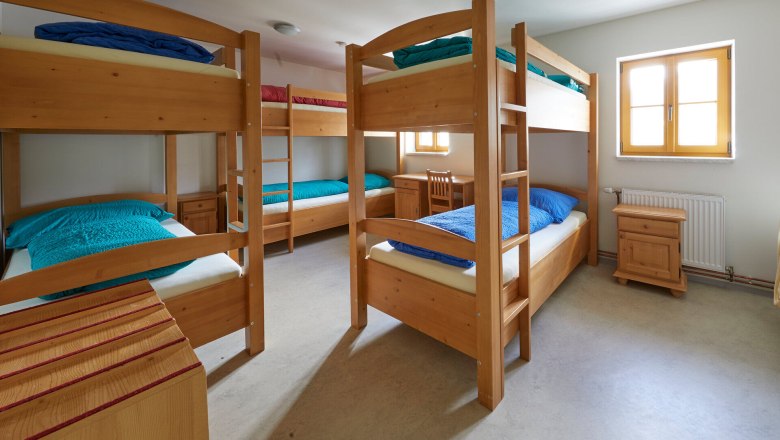 Multi-bed room with bunk beds and wooden furniture.