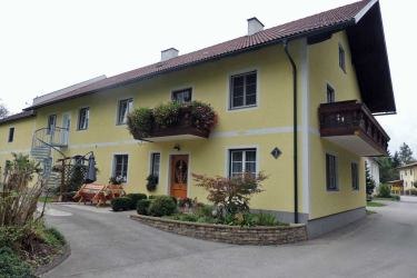 Yellow two-story house with balcony and garden.